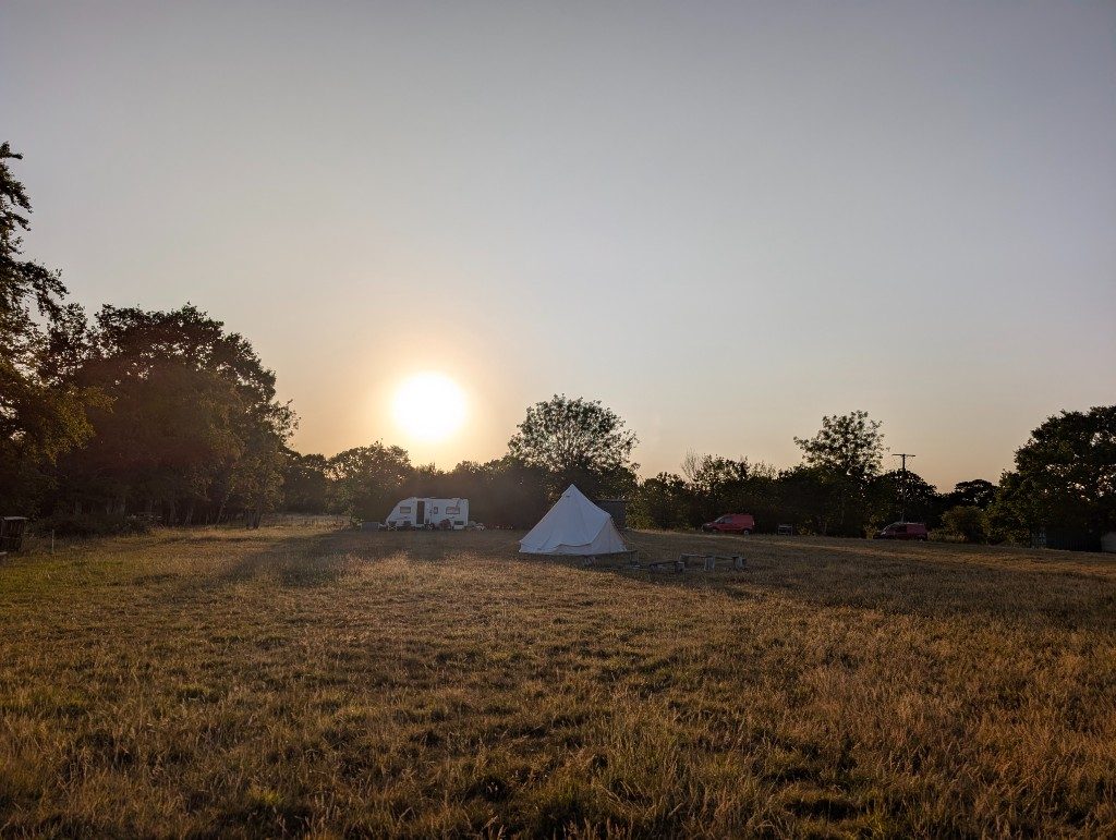 Bell tent and caravan in a golden field at sunset, Laughton Lodge